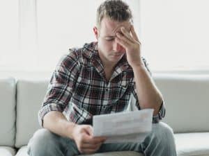 Shocked man holding some documents on sofa living room. Concept of How a Credit Card Debt Attorney Can Help You Reclaim Your Future